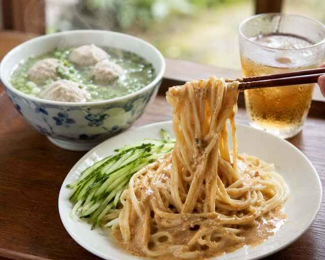 胡麻ダレたっぷりの台湾涼麺と、湯気が立ち上る貢丸スープのセット。箸で持ち上げた麺に濃厚な胡麻ダレが絡む本格台湾料理。