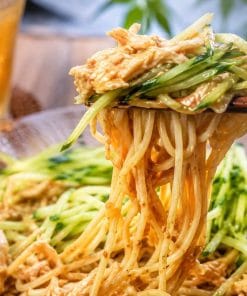 蒸し鶏ときゅうりをたっぷりのせた台湾風ごまだれ冷やし中華（涼麺）を箸で持ち上げた様子