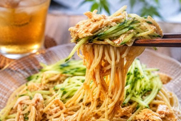 蒸し鶏ときゅうりをたっぷりのせた台湾風ごまだれ冷やし中華（涼麺）を箸で持ち上げた様子