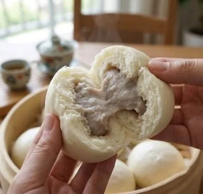 両手で半分に割ったホカホカのタロイモまんじゅう。中から自然な薄紫色のタロイモ餡があふれ、湯気が立ち上っている。背景には木のせいろと台湾茶器。